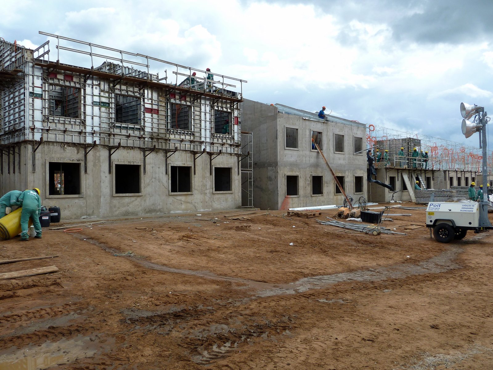 Canteiro de obras com fôrmas manuseáveis de alumínio montadas em um bloco de parede de concreto e blocos vizinhos já desformados